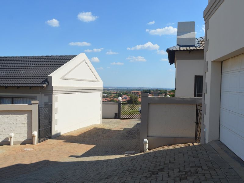 View of the paved driveway leading to the garage entrance, featuring perimeter walls and a clear view of the surrounding neighborhood.