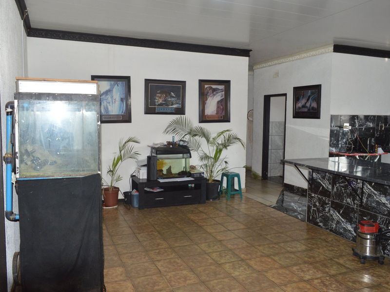 Open plan living and kitchen area featuring marble-look counter surfaces and ceramic tiled flooring, offering a functional layout with potential for modernization.