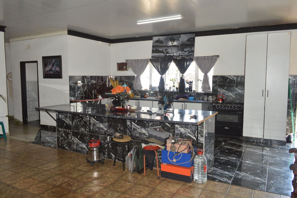 Spacious kitchen featuring a large marble-look tiled island, built-in oven, and extensive cabinetry with matching tiled backsplash and flooring.