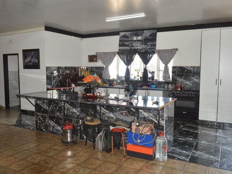 Spacious kitchen featuring a large marble-look tiled island, built-in oven, and extensive cabinetry with matching tiled backsplash and flooring.