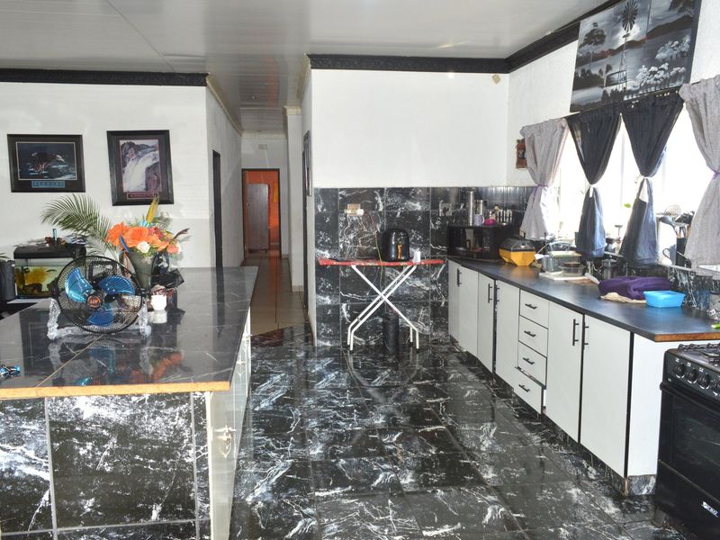 Kitchen featuring marble-look tiled flooring and backsplash, central island, and built-in cabinetry with a gas stove.