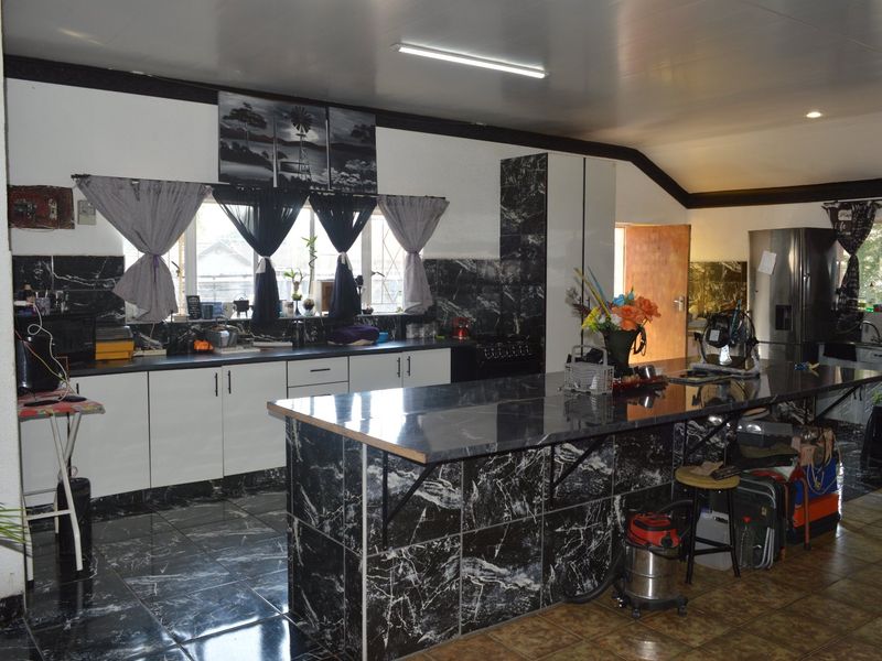 Spacious kitchen featuring a large marble-effect island, extensive cabinetry, and a tiled backsplash, offering a functional layout with potential for modern updates.
