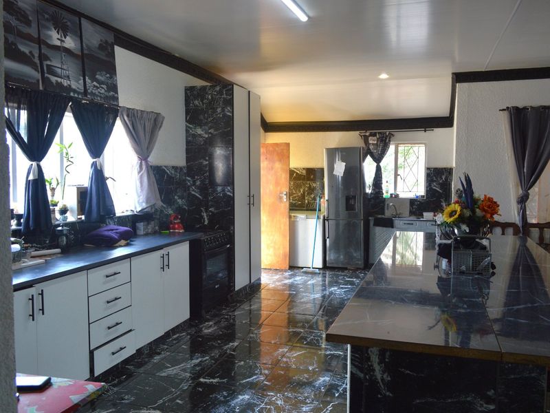 Spacious kitchen featuring marble-effect countertops and flooring, ample cabinetry, and a central island, offering a functional layout with a classic aesthetic.