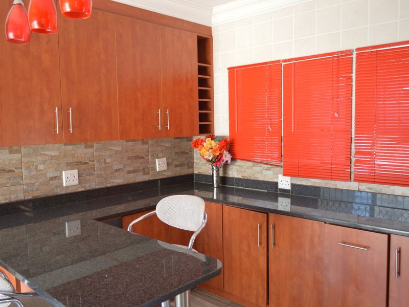 A kitchen featuring wooden cabinetry, granite countertops, and a stone tile backsplash, providing a functional workspace with integrated storage.