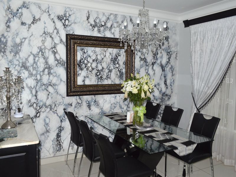 Formal dining room featuring a striking marble-effect feature wall, elegant crystal chandelier, and polished tiled flooring.