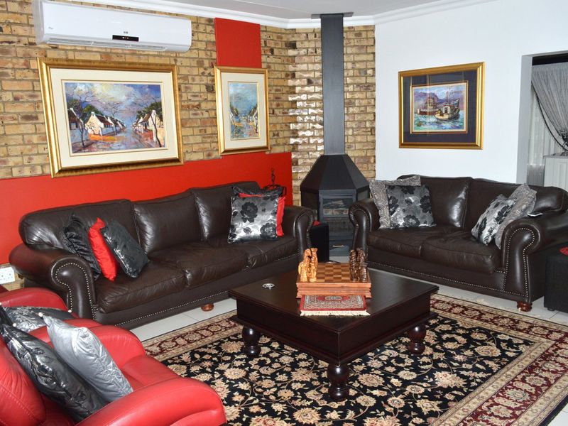 A living room featuring an exposed brick feature wall, a black freestanding fireplace, and a wall-mounted split-system air conditioning unit.
