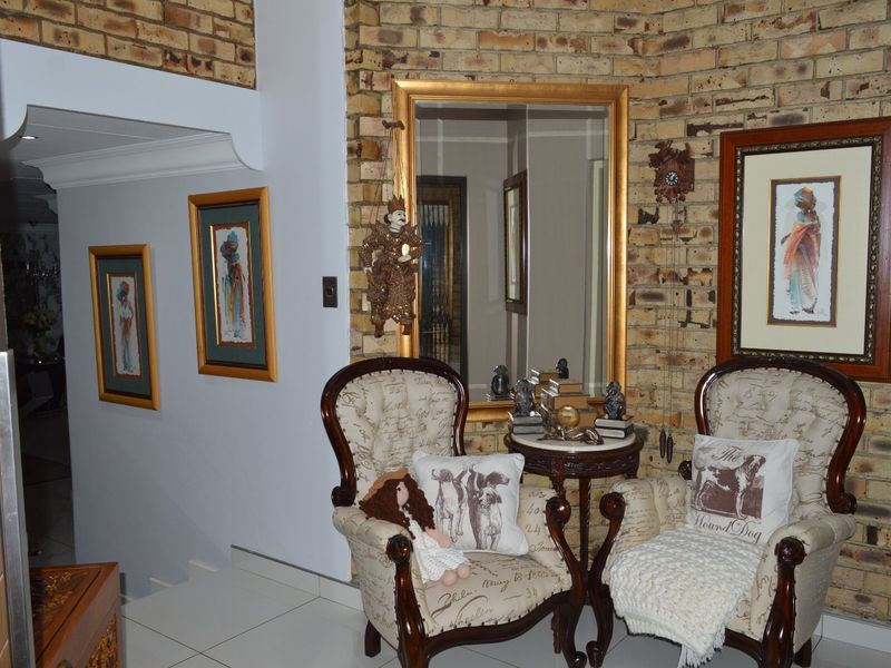 An inviting entrance hall featuring a textured exposed brick wall, tiled flooring, and a classic archway leading into the home.