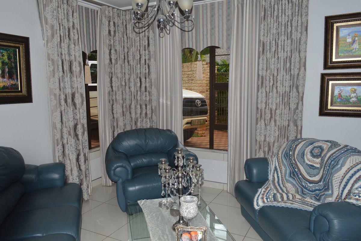 A living room featuring tiled flooring and arched windows that provide natural light and a view of the exterior driveway area.