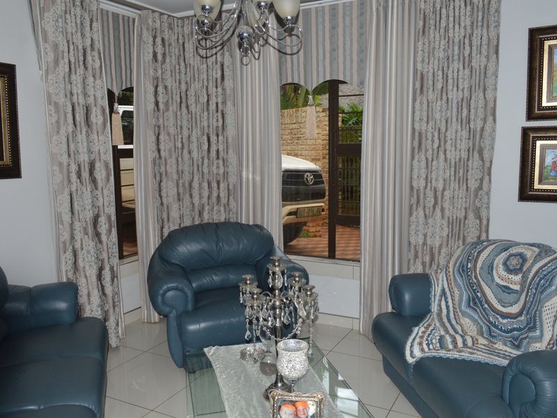 A living room featuring tiled flooring and arched windows that provide natural light and a view of the exterior driveway area.