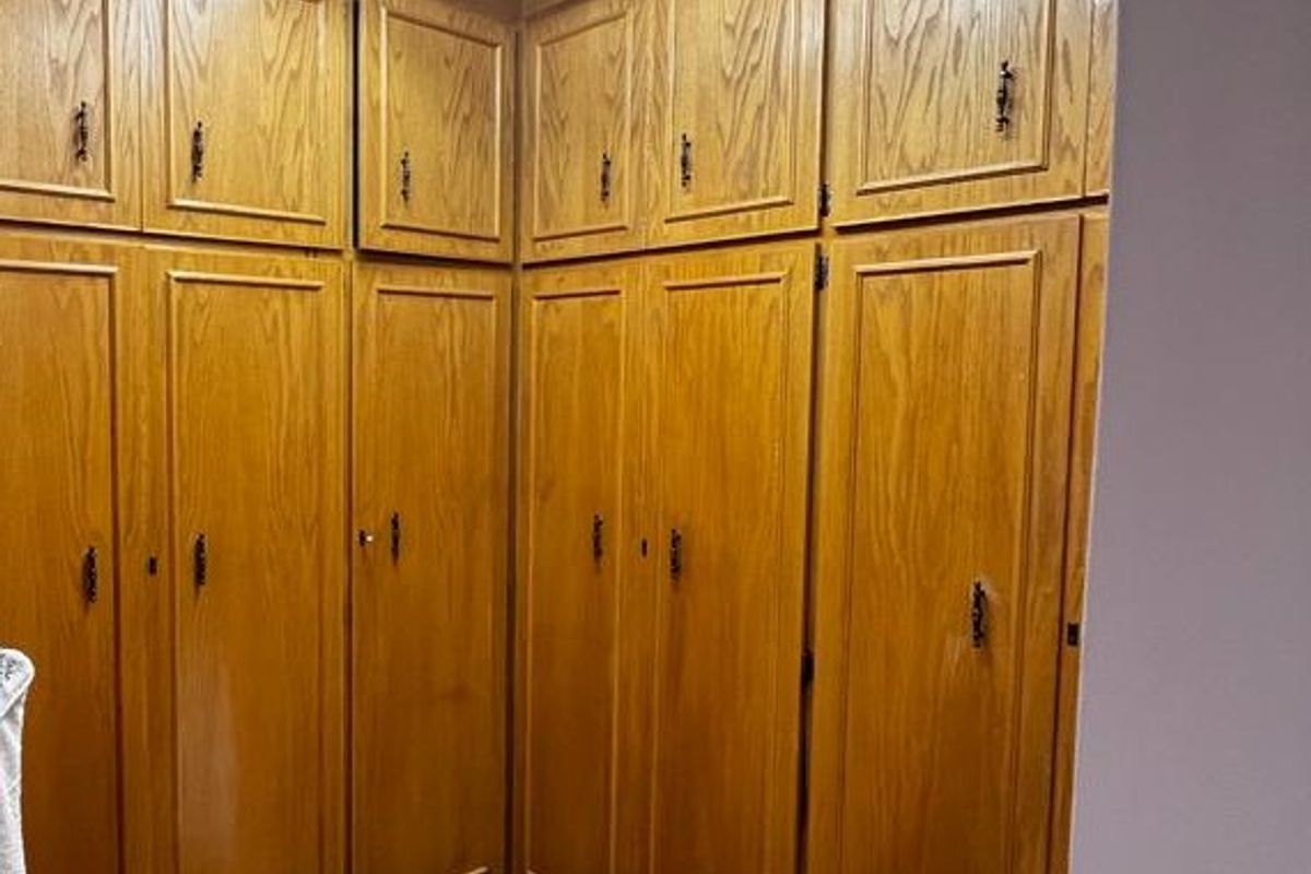 A bedroom featuring extensive built-in wooden cabinetry providing ample storage space, illuminated by a functional fluorescent light fixture.