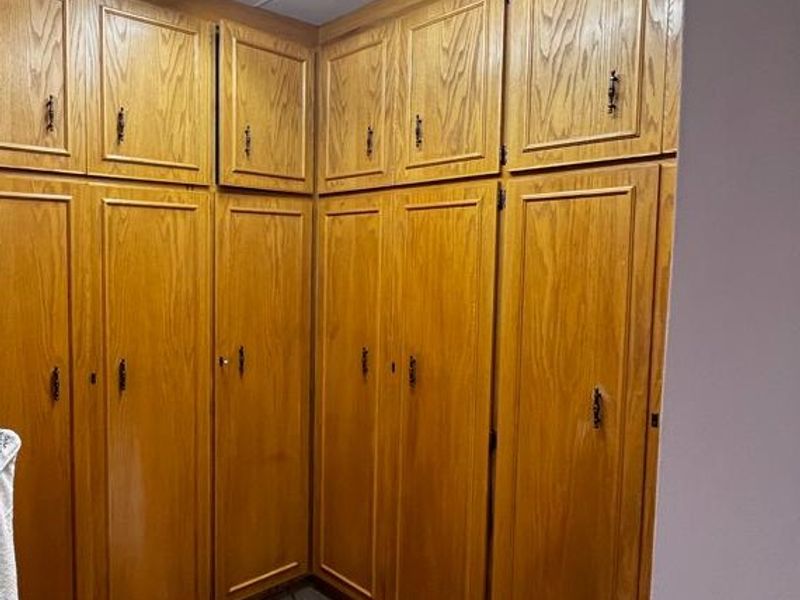 A bedroom featuring extensive built-in wooden cabinetry providing ample storage space, illuminated by a functional fluorescent light fixture.