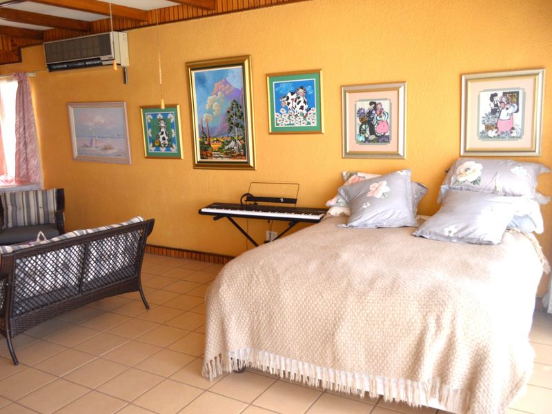 Spacious bedroom featuring tiled flooring, timber ceiling beams, and a wall-mounted air conditioning unit.