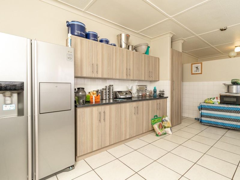A functional kitchen featuring light wood-tone cabinetry, tiled flooring, and a tiled splashback, providing ample storage and workspace.