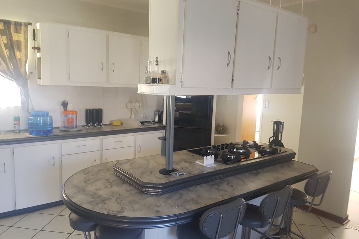 A functional kitchen featuring a central island with a built-in gas cooktop, ample cabinetry, and tiled flooring, offering a practical layout for daily use.