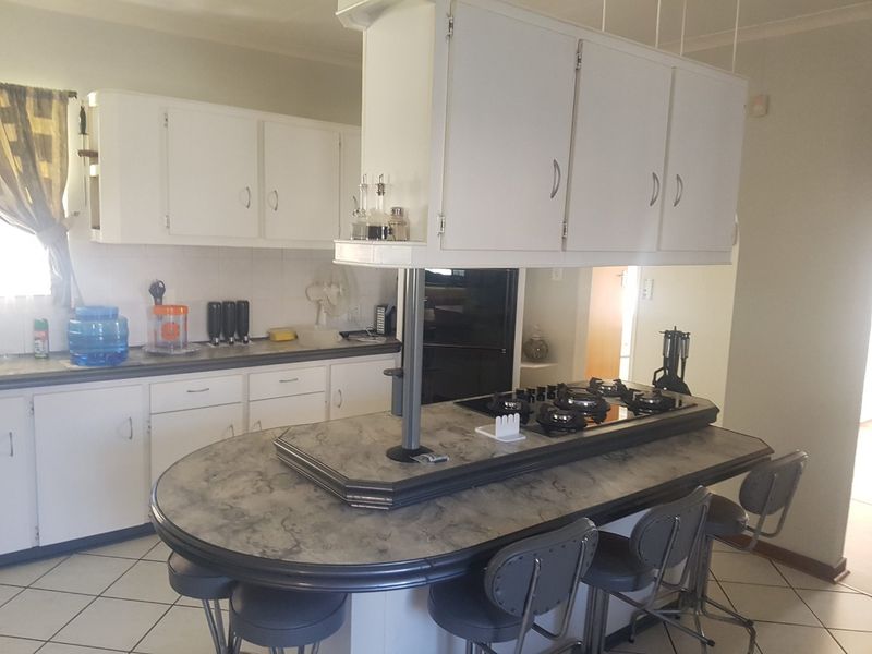 A functional kitchen featuring a central island with a built-in gas cooktop, ample cabinetry, and tiled flooring, offering a practical layout for daily use.