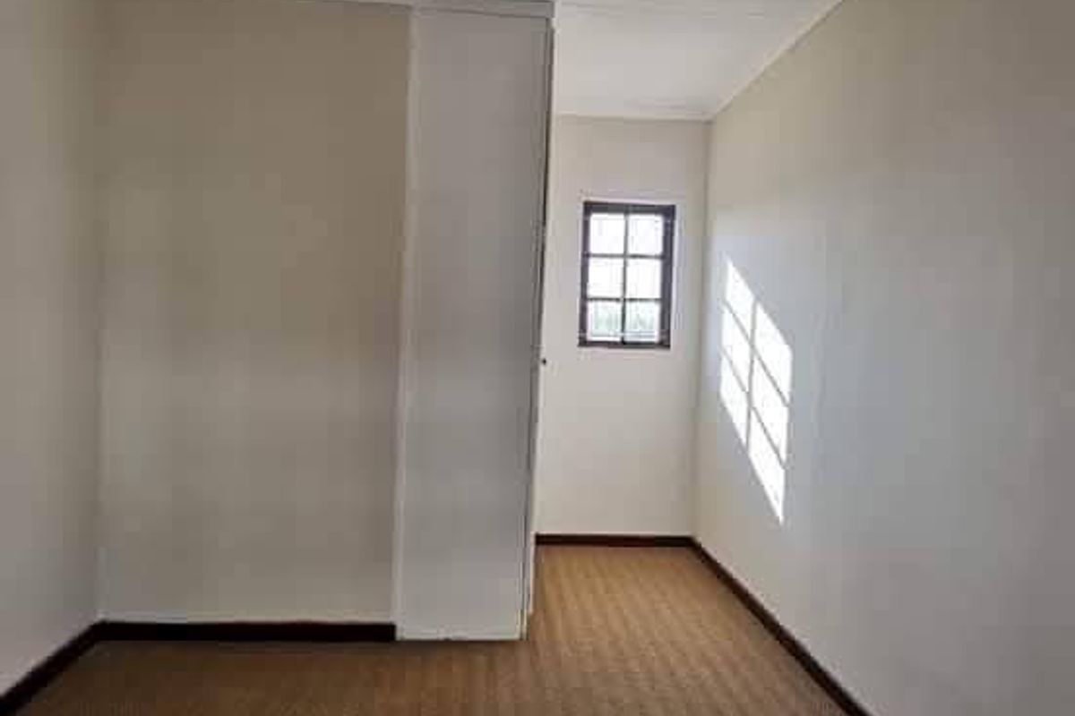 An empty bedroom featuring neutral walls, carpeted flooring, and a built-in wardrobe, offering a blank canvas for personalization.