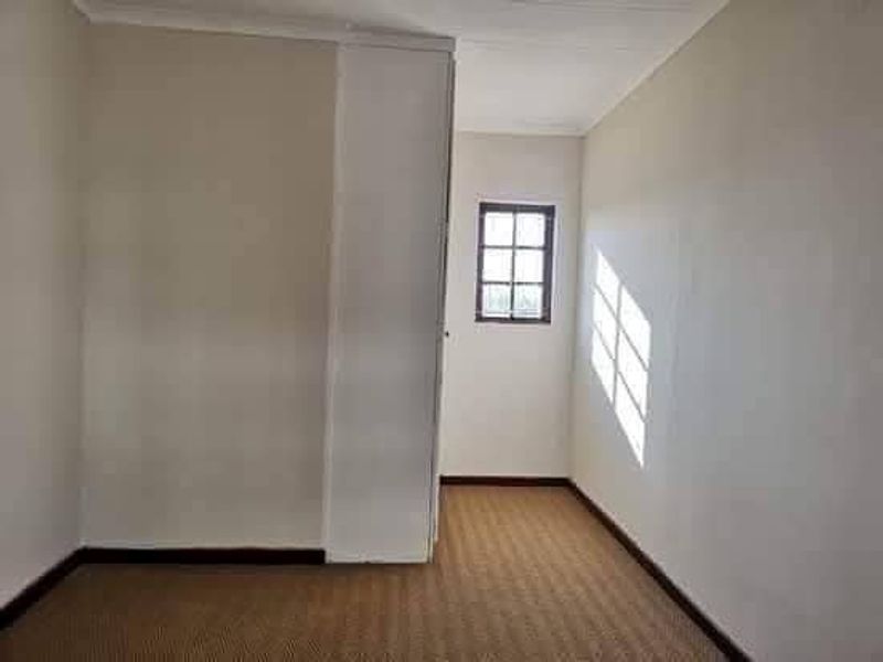 An empty bedroom featuring neutral walls, carpeted flooring, and a built-in wardrobe, offering a blank canvas for personalization.