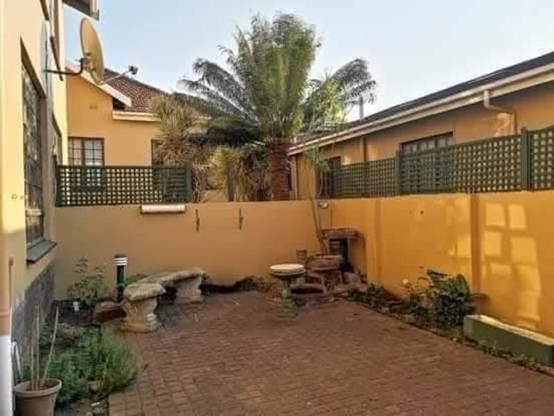 A private rear courtyard featuring paved flooring, boundary walls with trellis fencing, and established garden elements, offering a quiet outdoor space.