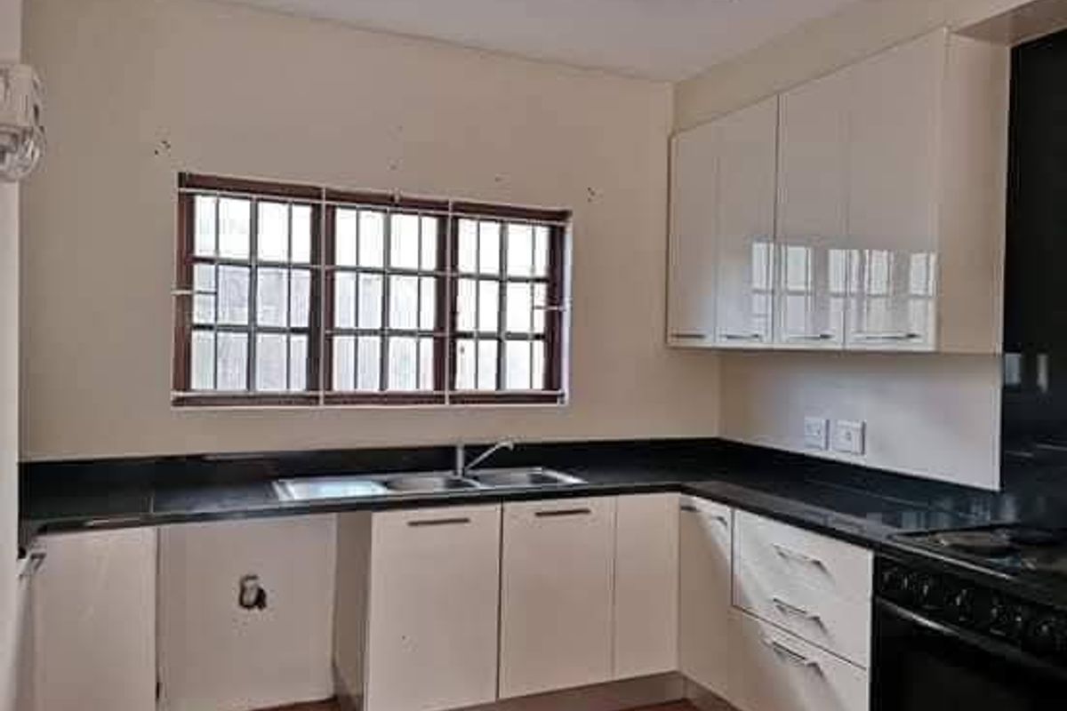 A functional kitchen featuring white cabinetry, black granite countertops, a double sink, and a built-in oven with hob.