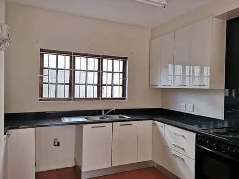 A functional kitchen featuring white cabinetry, black granite countertops, a double sink, and a built-in oven with hob.