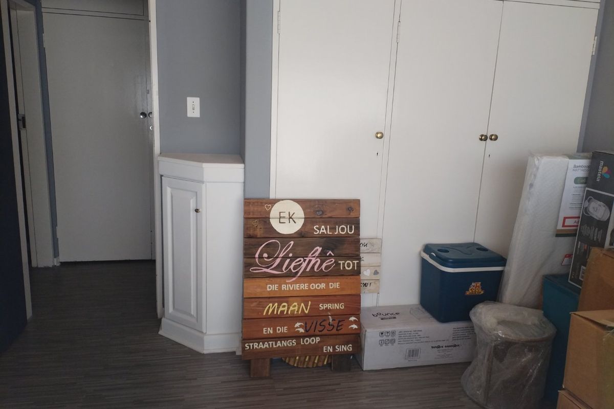 A bedroom featuring built-in cupboards, laminate flooring, and a corner cabinet, offering functional storage space.