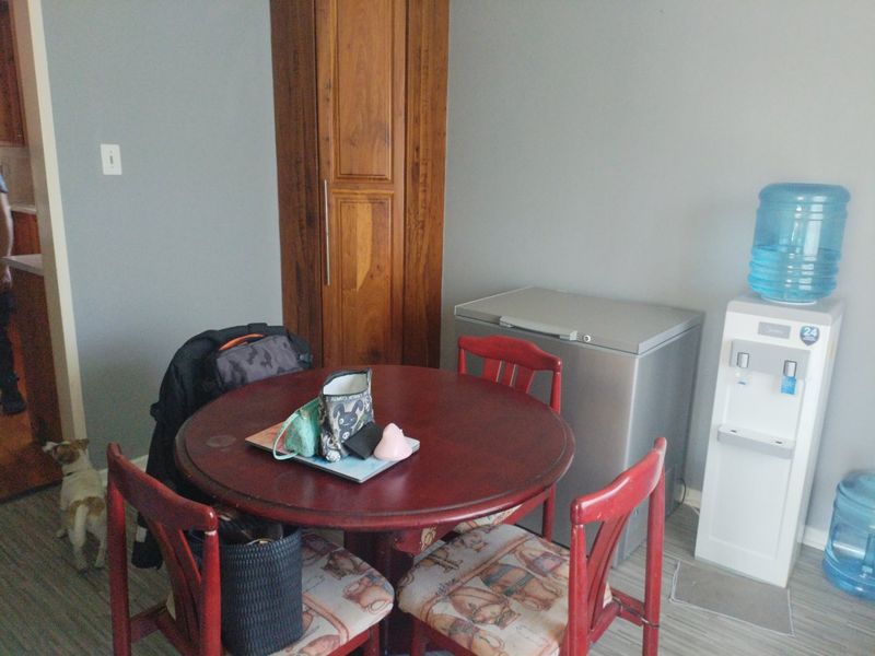 A dining area featuring laminate flooring and a built-in wooden storage cabinet, providing a functional space for meals.
