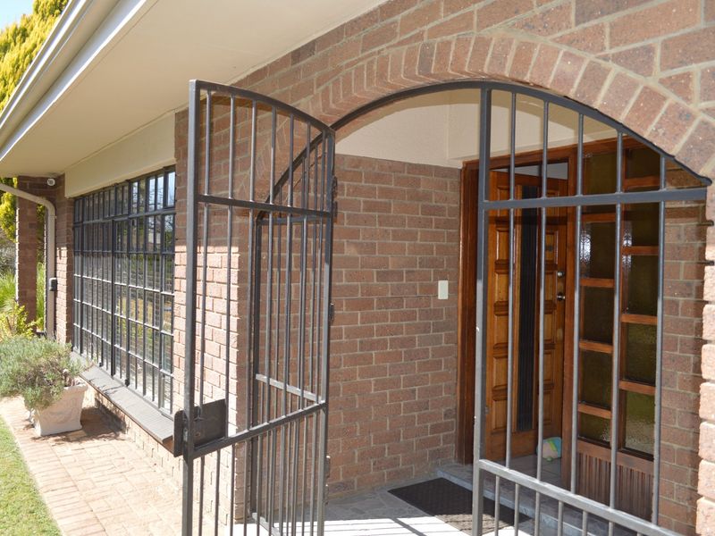 Front entrance featuring a classic brick facade, arched entryway, and a secure wrought iron gate leading to a solid timber front door.