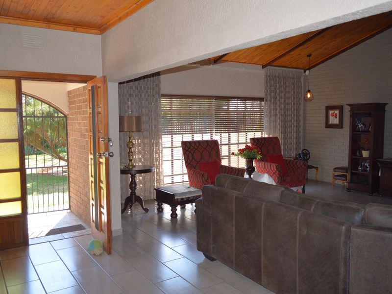 Spacious living area featuring a vaulted timber-lined ceiling, tiled flooring, and an exposed brick wall, creating a warm and inviting atmosphere.