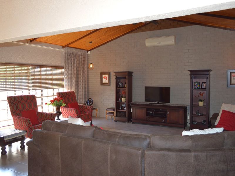 Spacious living room featuring a high exposed timber ceiling, brick feature wall, tiled flooring, and a wall-mounted air conditioning unit.