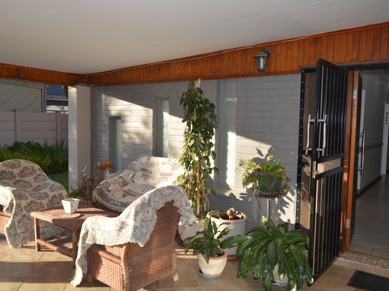 A covered patio area featuring tiled flooring, timber ceiling accents, and a secure metal entrance gate, providing a functional outdoor transition space.