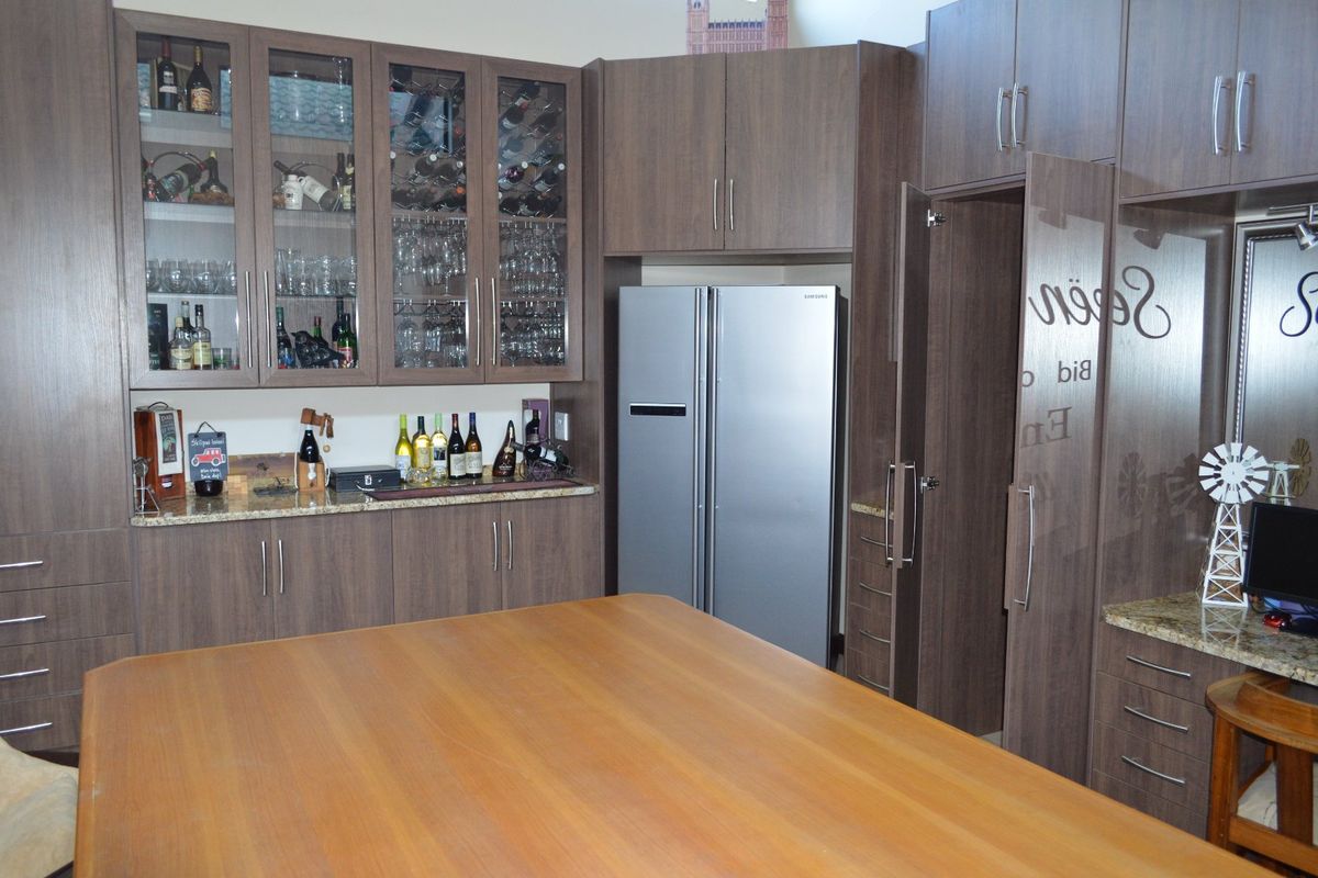A well-appointed kitchen featuring extensive dark wood cabinetry, granite countertops, and dedicated glass-front display storage for glassware and wine.