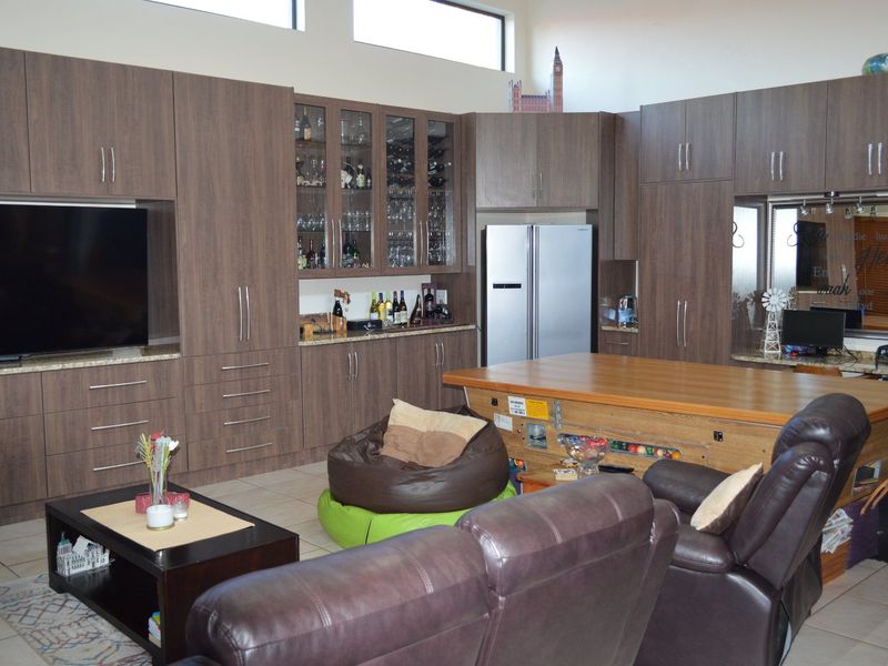 Spacious open-plan living area featuring extensive built-in cabinetry, granite countertops, glass display units, and high clerestory windows providing ample natural light.