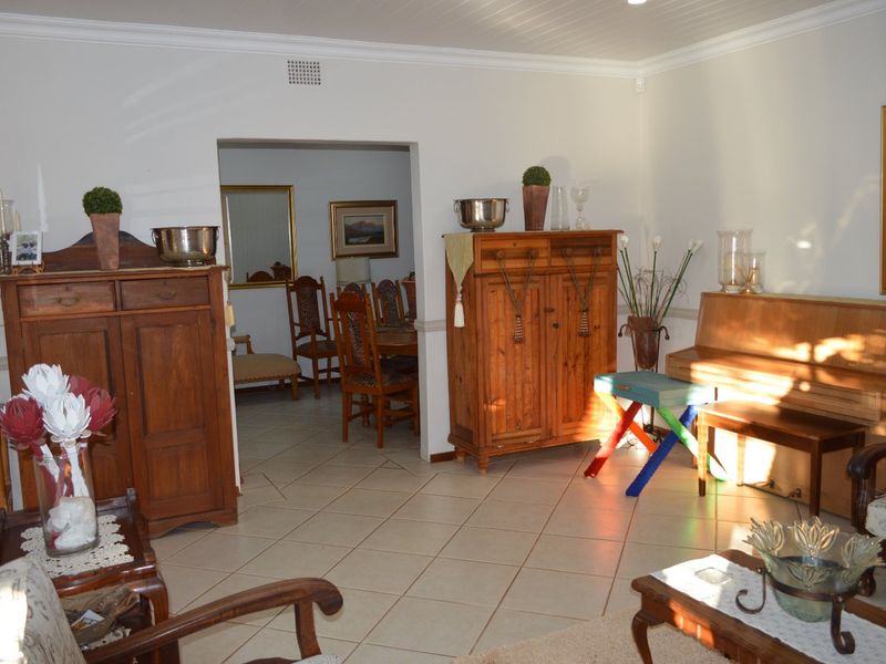 A spacious living area featuring neutral tiled flooring and coved ceilings, with an open transition into the adjacent dining room.