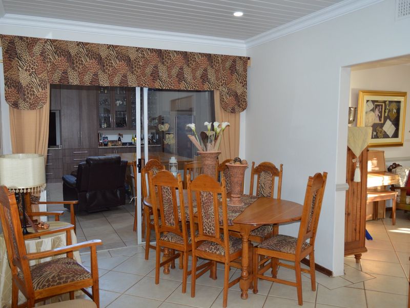 A dining room featuring tiled flooring and a sliding glass door leading to an adjacent kitchen area with a tongue and groove ceiling.