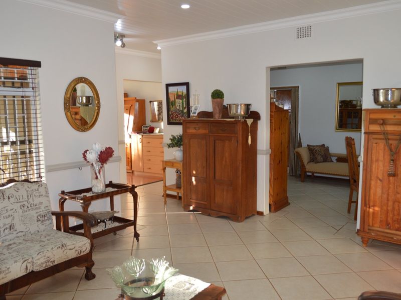 Spacious living area featuring tiled flooring, recessed lighting, and decorative chair rail molding, with an open-plan flow into the adjacent kitchen and dining spaces.
