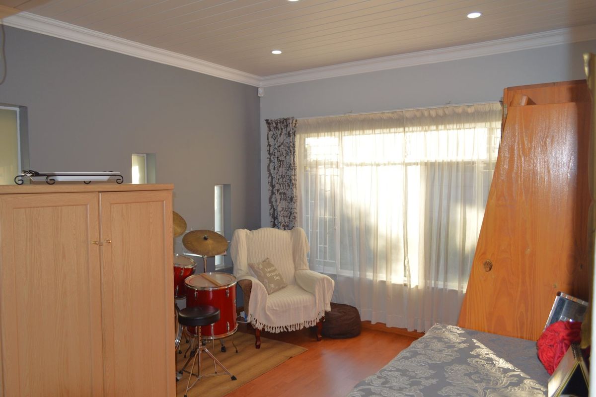A well-lit bedroom featuring laminate flooring, a tongue and groove ceiling with recessed lighting, and large windows allowing for ample natural light.