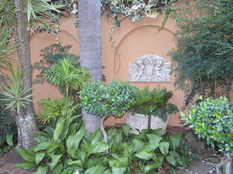 A landscaped garden area featuring arched wall niches, a decorative stone relief, and established greenery.