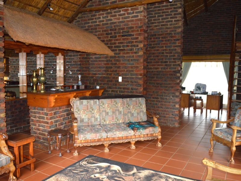 Rustic bar area featuring exposed brick walls, a thatched roof detail, and a built-in bar counter, with tiled flooring throughout.