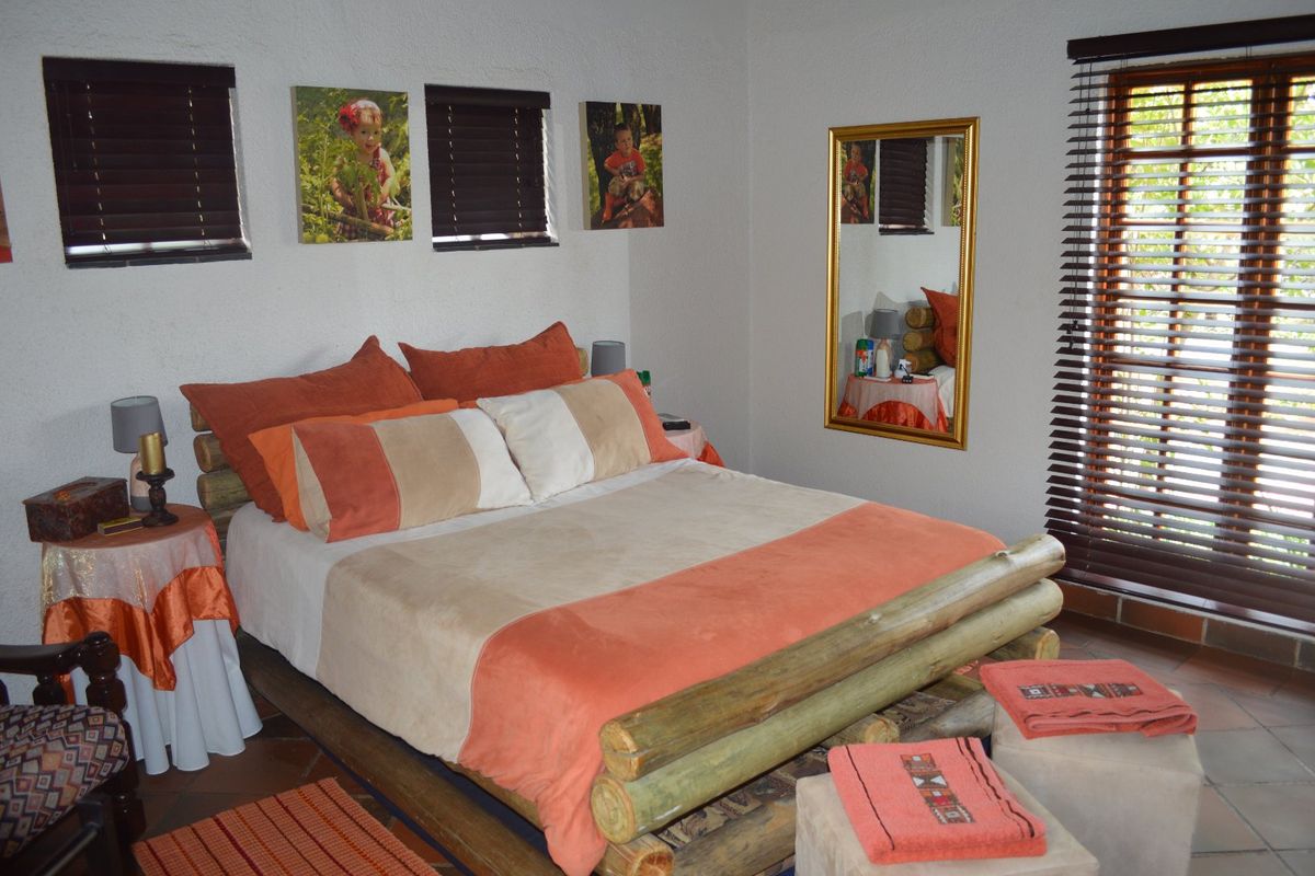 A bedroom featuring tiled flooring and wooden venetian blinds, providing a functional and comfortable sleeping space.