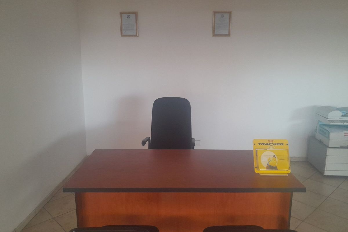 A functional commercial office space featuring tiled flooring and a simple layout, suitable for a professional work environment.