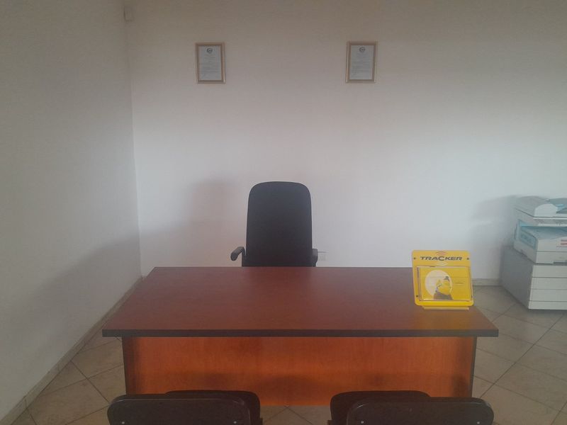 A functional commercial office space featuring tiled flooring and a simple layout, suitable for a professional work environment.