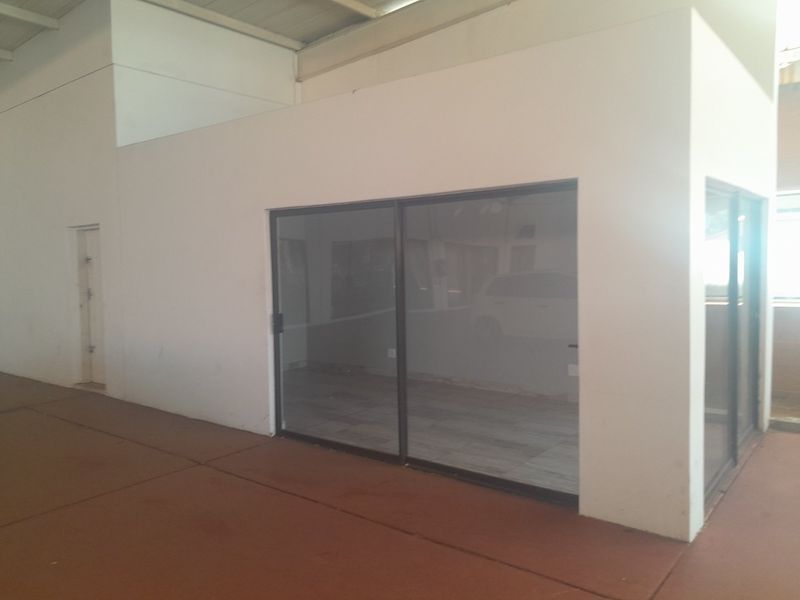 An empty commercial office space featuring modern sliding glass doors and tiled flooring, suitable for a professional workspace or meeting room.