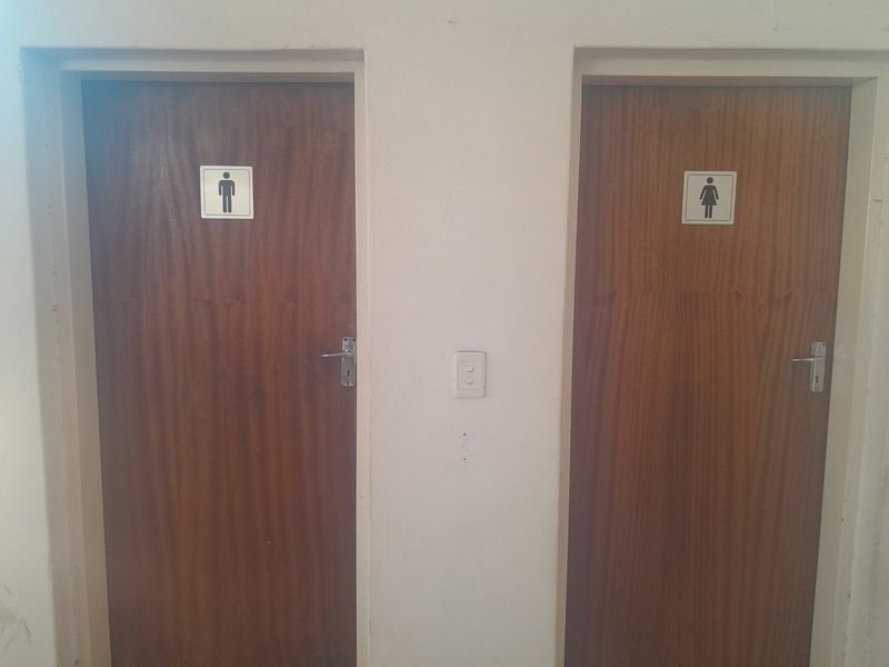 A hallway view featuring two wooden doors with male and female restroom signage.