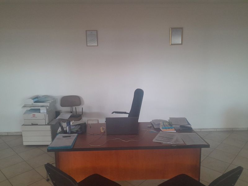A functional commercial office space featuring tiled flooring and neutral wall finishes, suitable for a professional work environment.