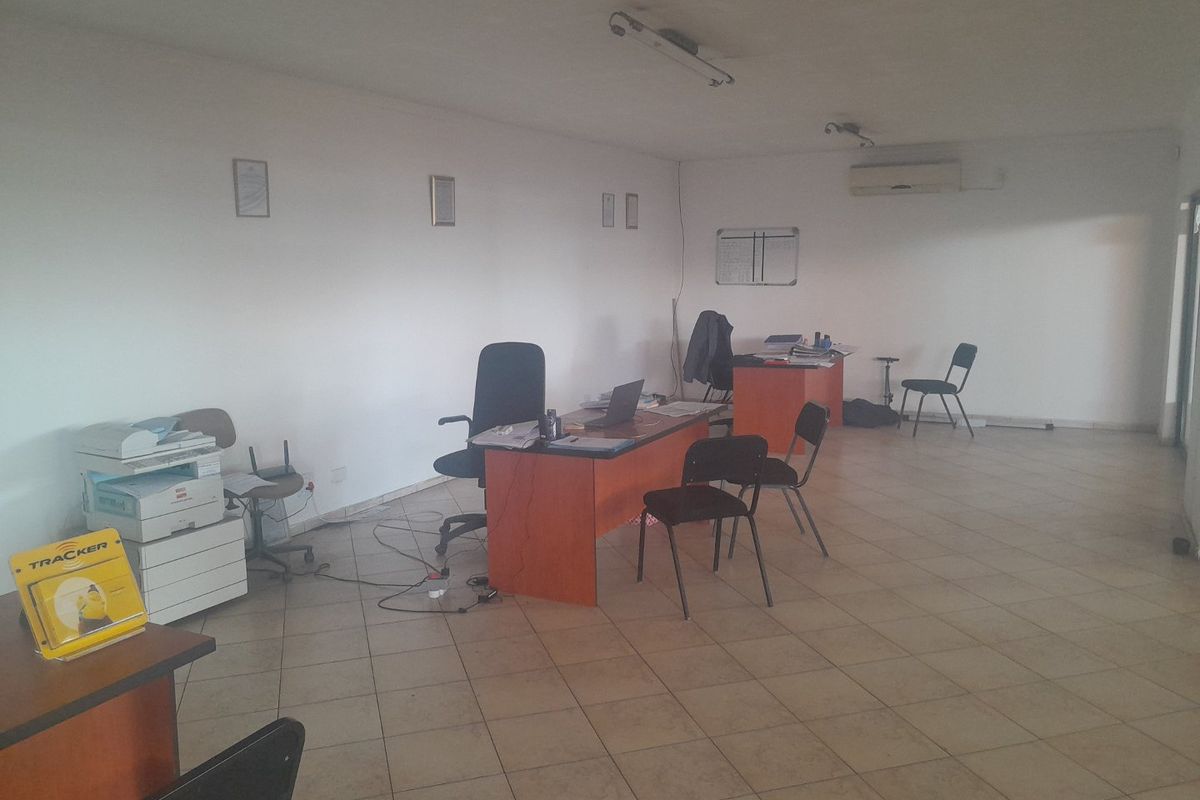 A functional commercial office space featuring tiled flooring and a wall-mounted air conditioning unit, suitable for a professional work environment.