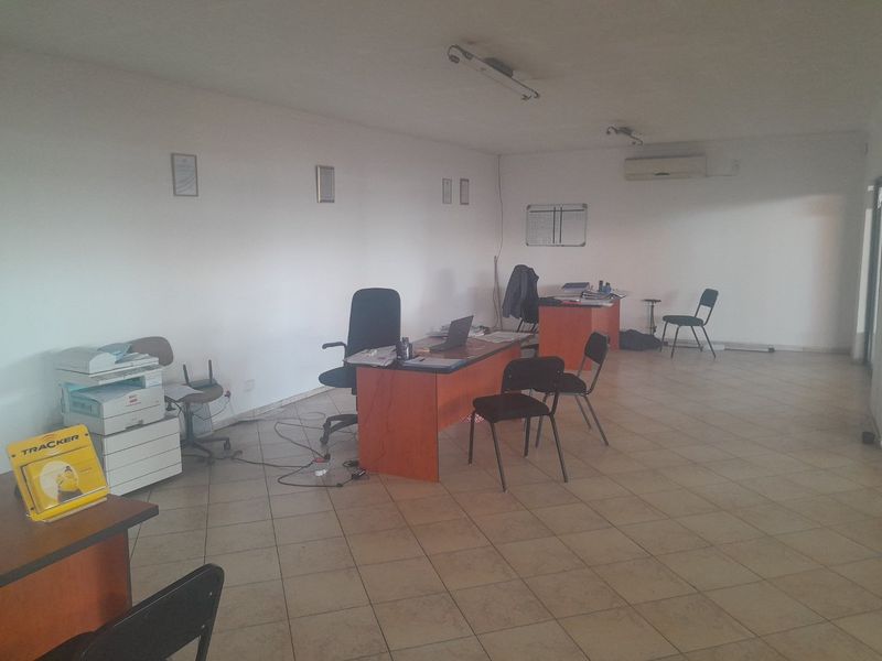A functional commercial office space featuring tiled flooring and a wall-mounted air conditioning unit, suitable for a professional work environment.