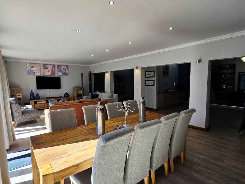 Spacious open-plan living and dining area featuring modern laminate flooring, recessed downlighting, and a neutral color palette.