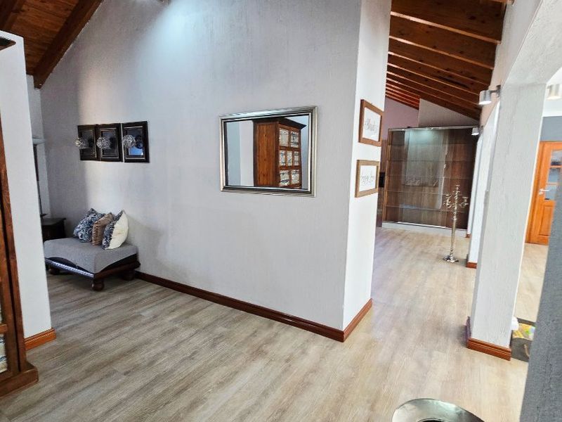 Spacious living area featuring high vaulted ceilings with exposed timber beams and modern laminate wood flooring throughout.