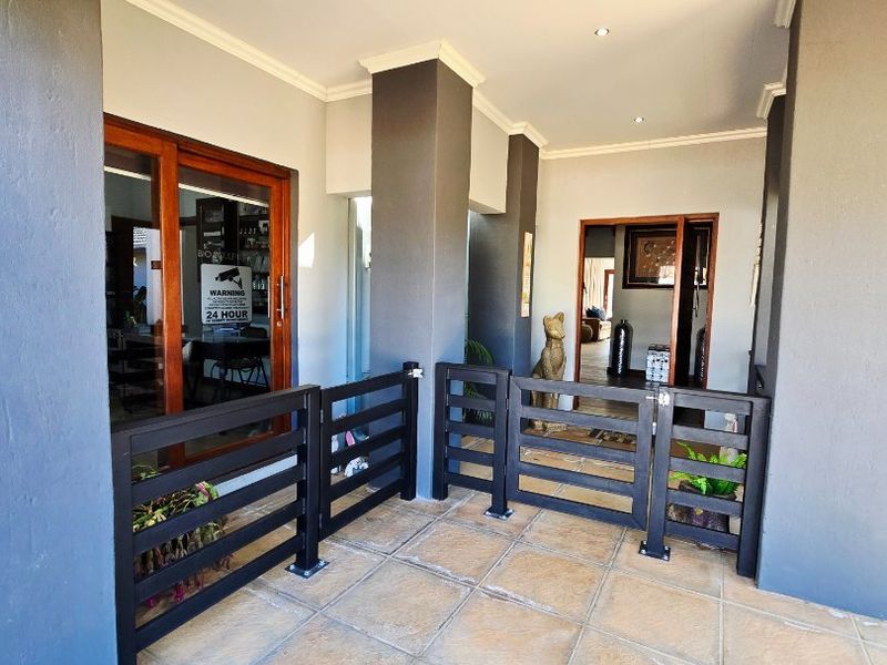 A covered patio area featuring tiled flooring, recessed downlights, and a timber balustrade, providing a transition space between the interior and exterior.