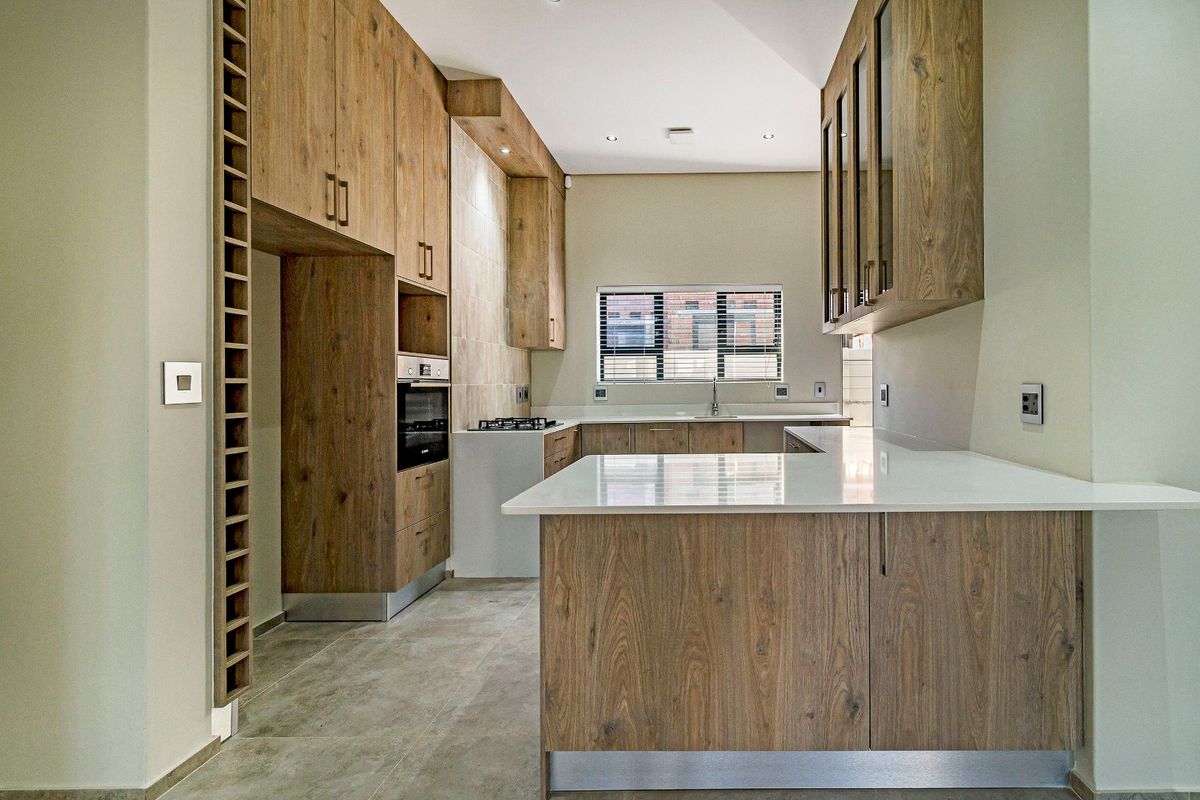 Modern kitchen featuring wood-grain cabinetry, stone countertops, built-in oven, gas hob, and tiled flooring in a clean, contemporary layout.